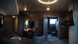 Ein modernes, schummriges Zimmer mit einem großen Spiegel, einem kleinen Schreibtisch mit Wasserkocher und einer Bar mit Flaschen.