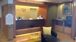 A hotel reception area with a reception desk, a chair, a small table, and a computer. - Hotel 1-2-3 Shimada (Shimada)
