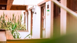 A traditional building with a wooden ceiling, a window with a view, and a door with a sign. - Plaza Magnolias Suites (San Cristóbal de las Casas)