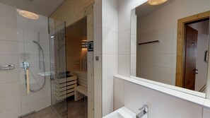 A modern bathroom with a glass shower enclosure, a wooden bench, and a large mirror.