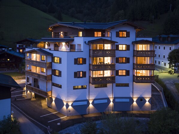 A multi-story hotel with balconies, a parking area, and a view of the surrounding landscape.