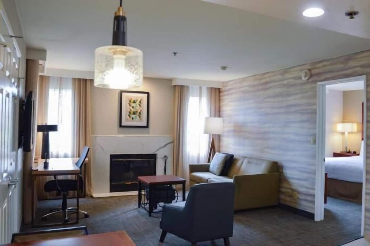 Une chambre d’hôtel équipée d’une cheminée, d’un bureau, d’un canapé, d’un lit et d’un couloir menant à une autre pièce.