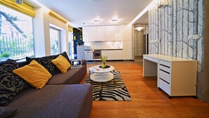 Ein modernes Wohnzimmer mit Sofa, Couchtisch und Küchenbereich, inklusive Schränke und Arbeitsplatte.