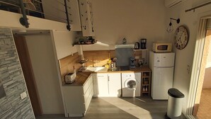 Une cuisine compacte équipée d’un lave-linge, d’un four à micro-ondes et d’un réfrigérateur.