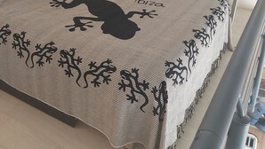 Une chambre à coucher avec un lit, une table de chevet, une lampe, une chaise et une fenêtre avec des rideaux.