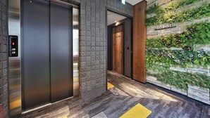 An elevator with a digital display, a wall with a vertical garden, and a wooden door. - Micro Hotel (Taichung)
