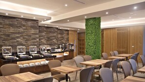A modern restaurant with a stone wall, a green vertical garden, and wooden tables and chairs. - Micro Hotel (Taichung)