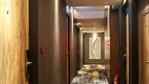 A hotel hallway with wooden doors, a patterned wall, and a fire extinguisher. - Micro Hotel (Taichung)