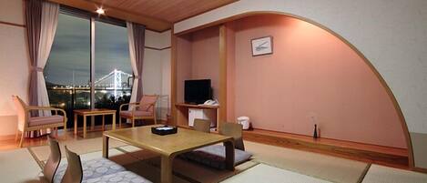 Um quarto tradicional japonês com tatames, uma mesa baixa e assentos.