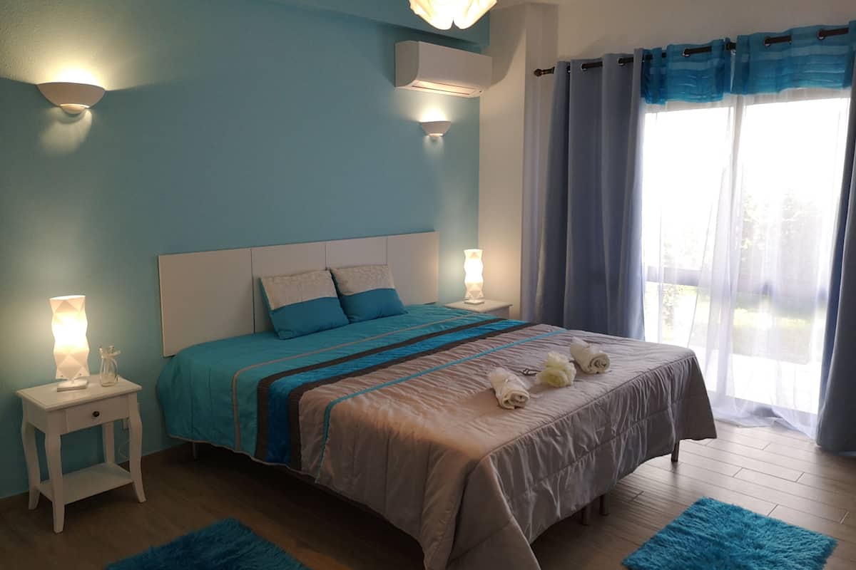 A bedroom with a bed, bedside tables, and a window with curtains.