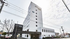 Un hotel moderno con una fachada blanca destacada, múltiples ventanas y un techo plano.