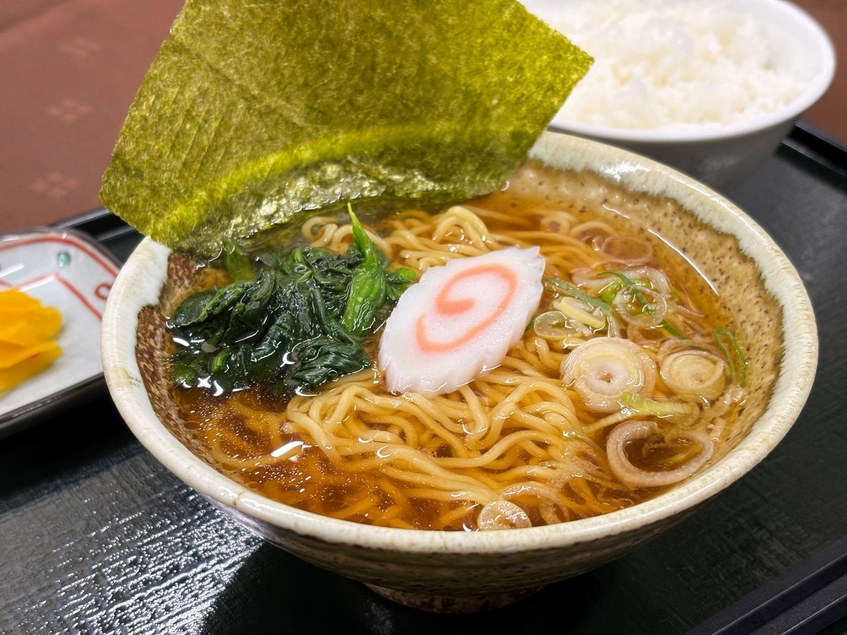 A bowl of ramen with noodles, broth, and toppings like seaweed and scallions.