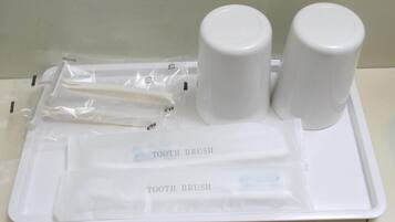 Una bandeja con cepillo de dientes, pasta dental y una taza, probablemente en el baño de un hotel.