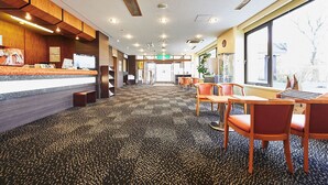 Un vestíbulo de hotel con recepción, zona de estar y ventanas amplias.