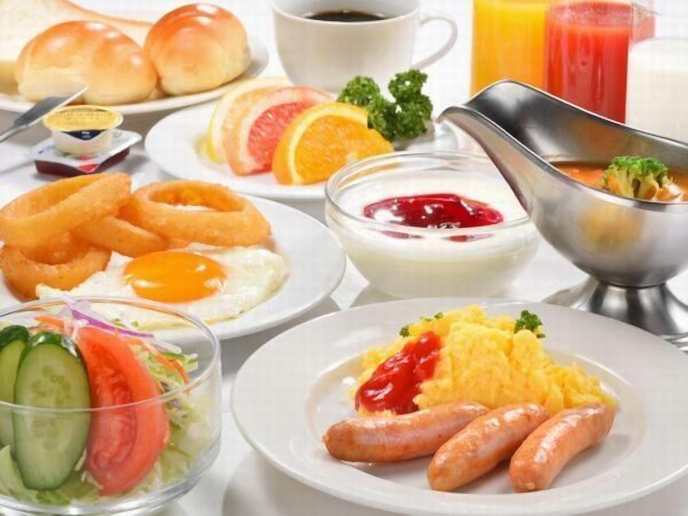 A breakfast setting with various dishes including eggs, sausages, and a salad.