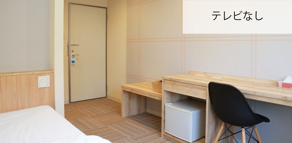 A hotel room with a bed, a desk, a chair, and a small cabinet.