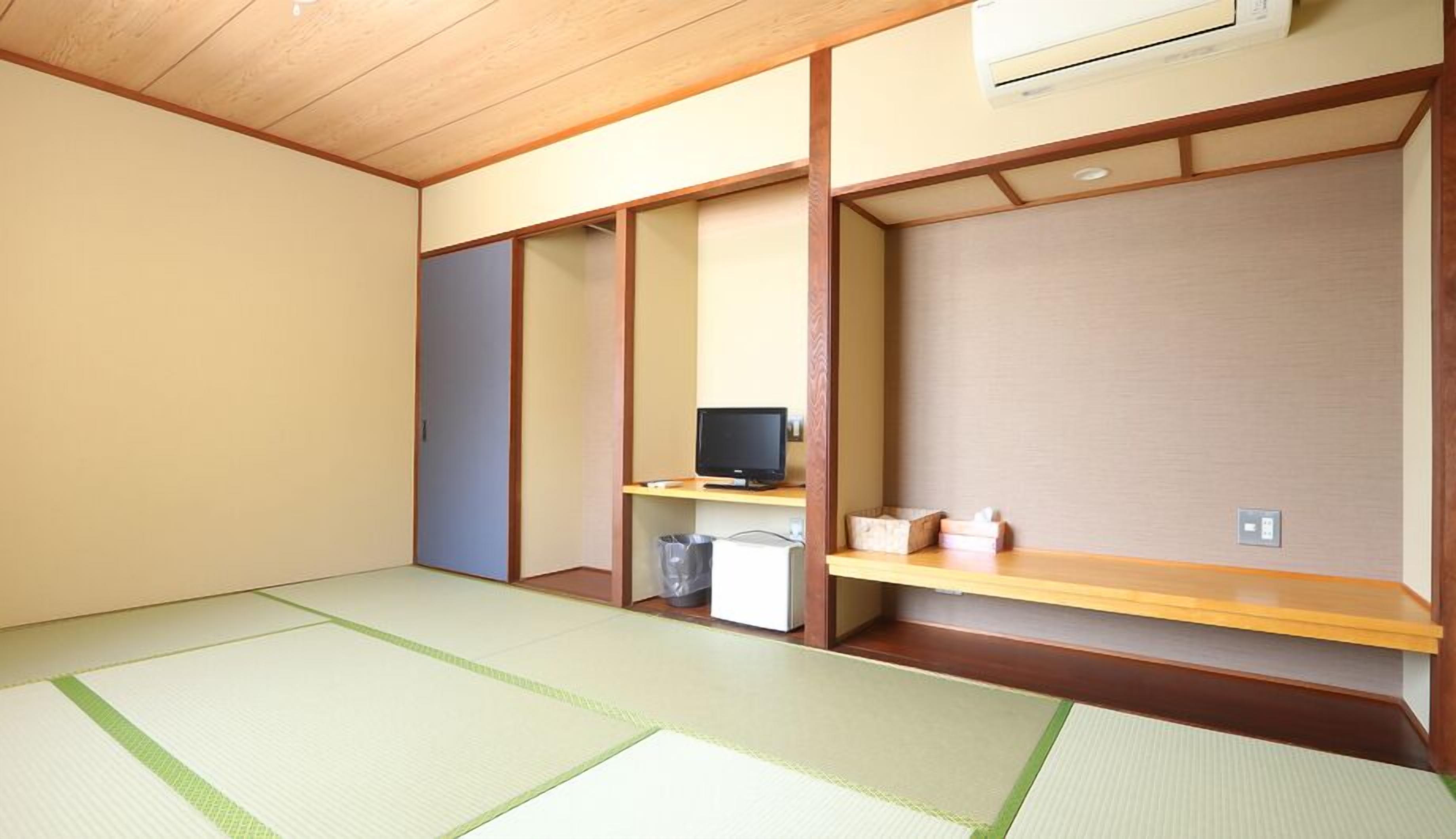 A room with tatami flooring, a television on a low shelf, and a small trash bin.