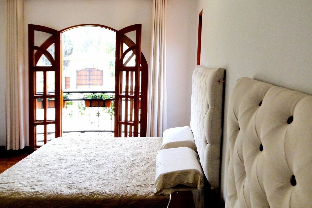 A bedroom with a bed, a wooden door, and a view of the outside.