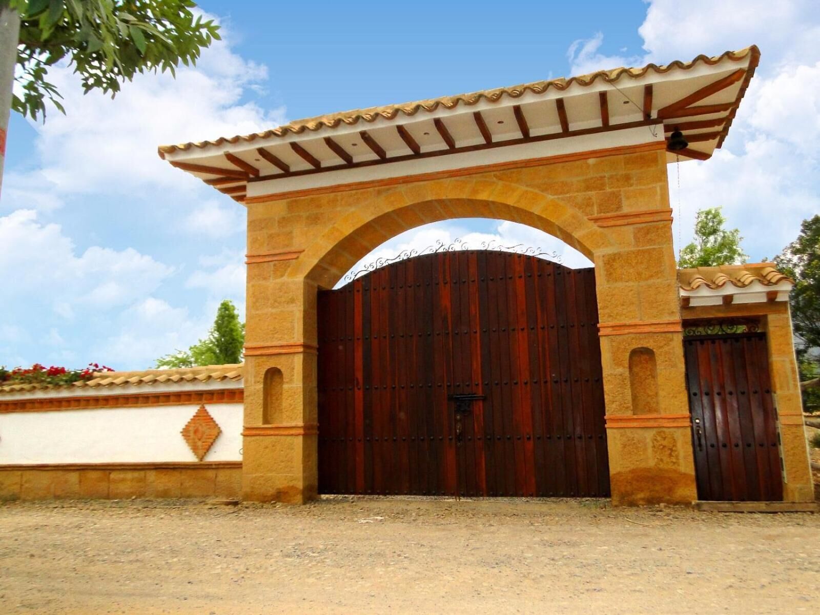 A large, ornate wooden gate with an arched entrance, set within a stone wall.