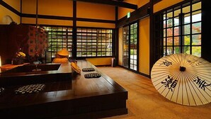 Une pièce de style japonais traditionnel, avec un sol recouvert de tatamis, une petite table en bois et une grande porte coulissante en papier de riz (shoji).