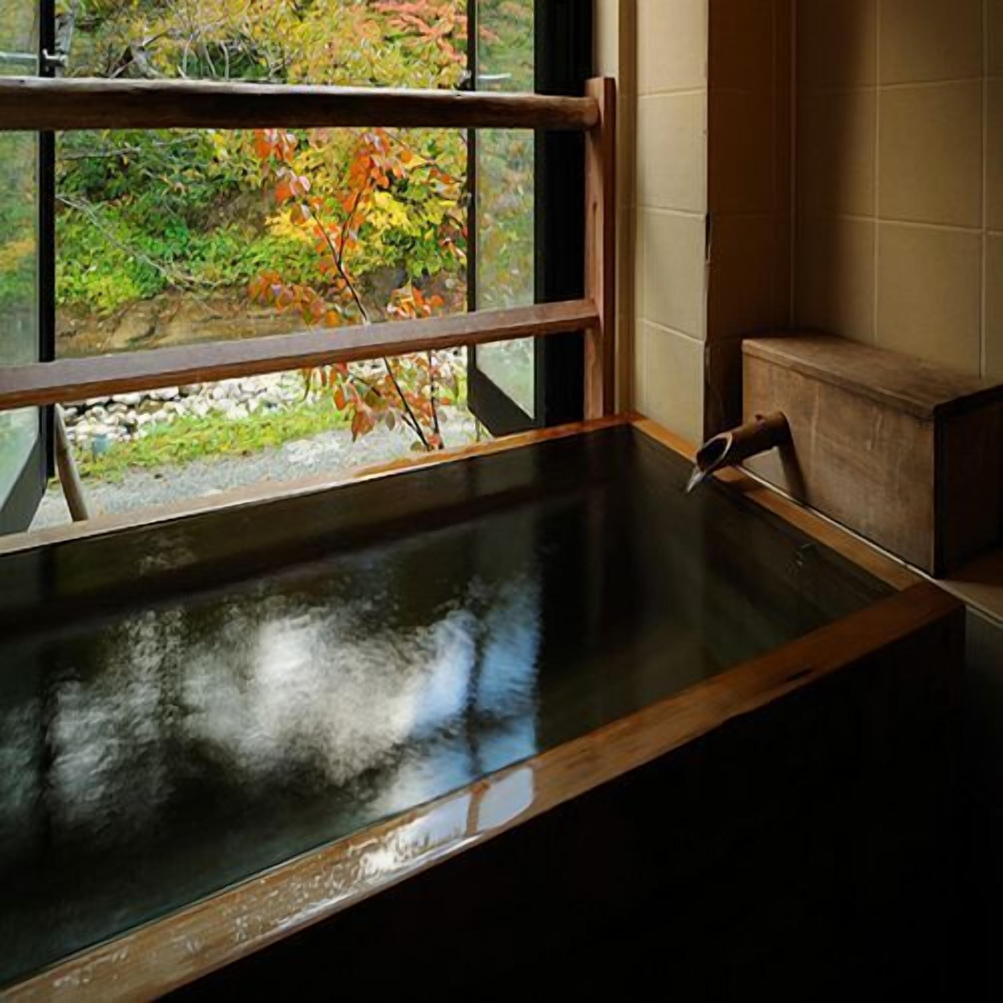 A room with a window, a wooden bench, and a view of foliage outside.