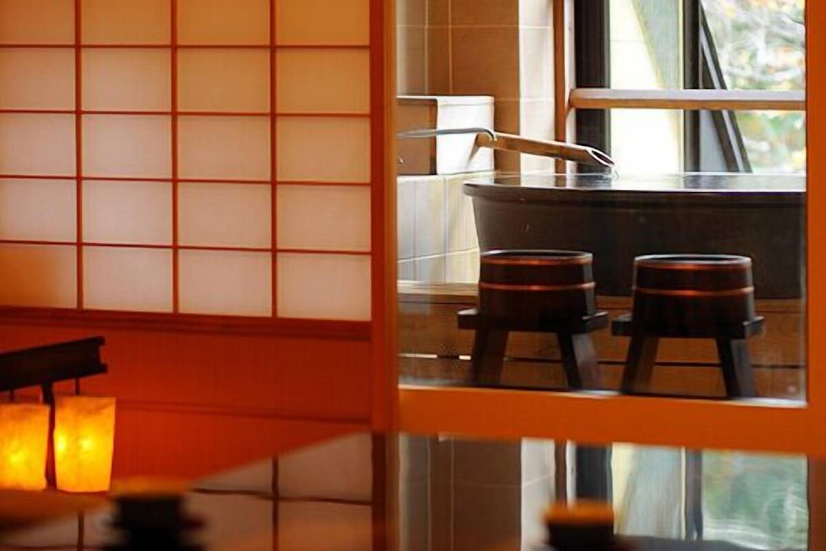 Ein traditioneller japanischer Raum mit Tatami-Bodenbelag, einem niedrigen Tisch und einem Fenster mit Blick ins Freie.