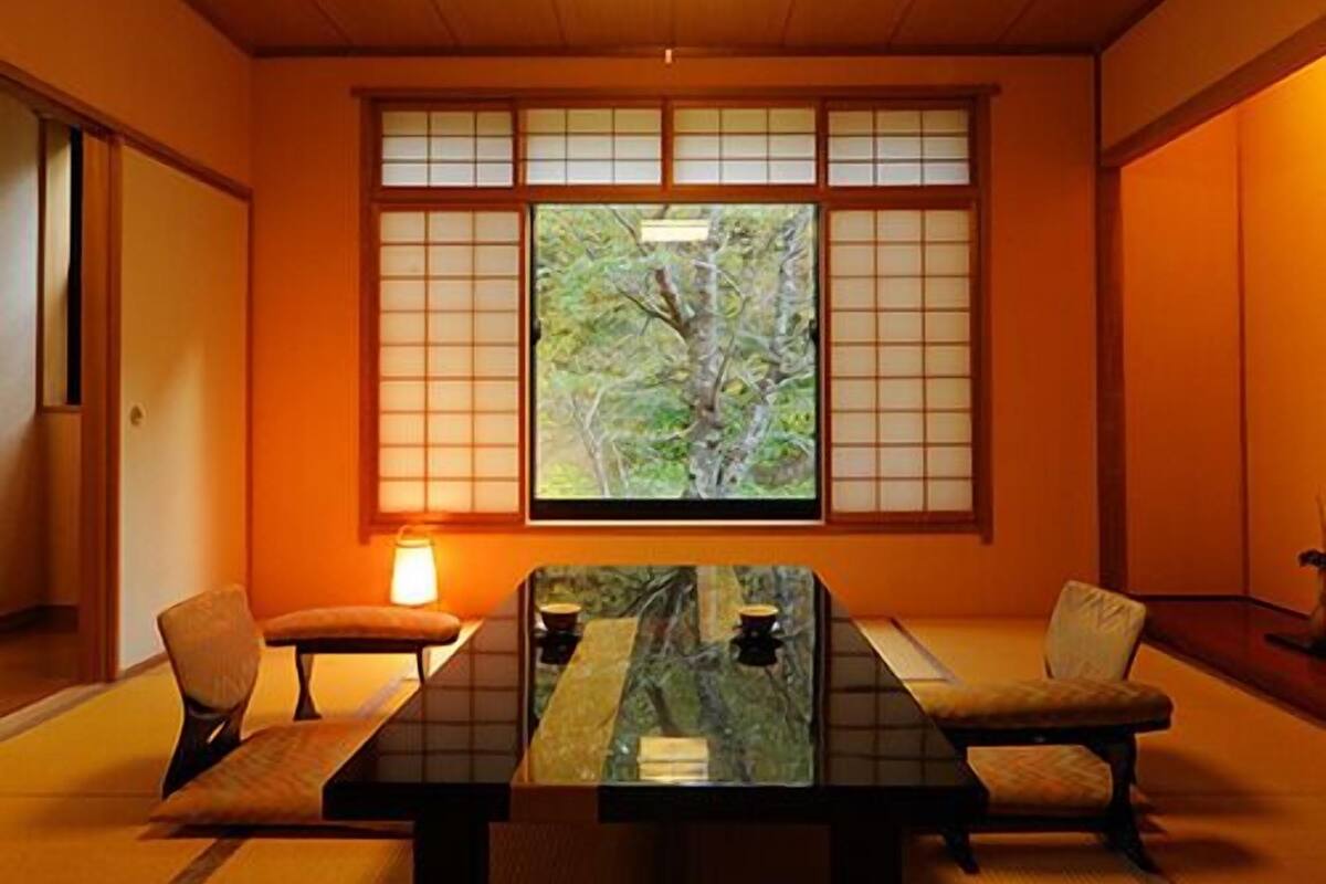 Ein traditioneller japanischer Raum mit Tatami-Böden, einem niedrigen Tisch und verschiebbaren Türen.