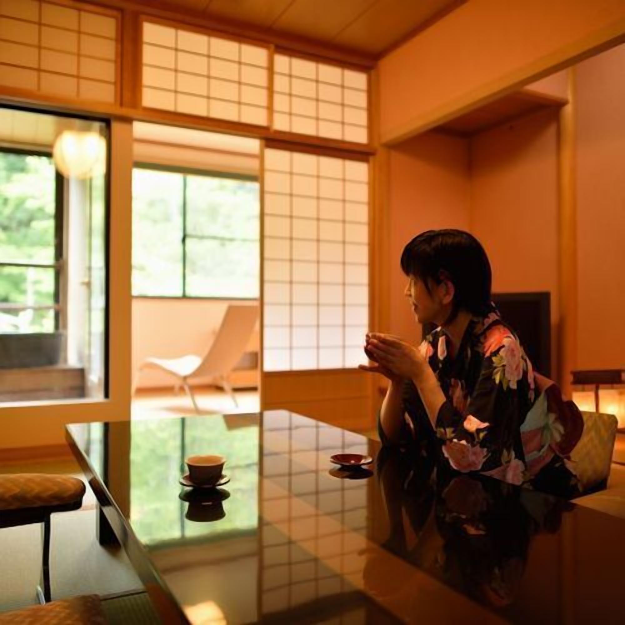 A traditional Japanese room with tatami flooring, a low table, and a sliding door leading to a garden.