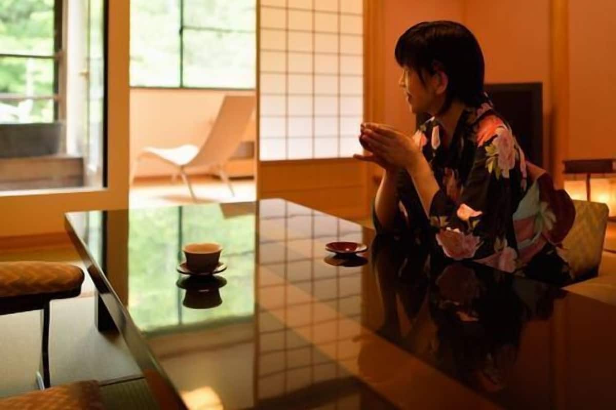 A traditional Japanese room with tatami flooring, a low table, and a sliding door leading to a garden.