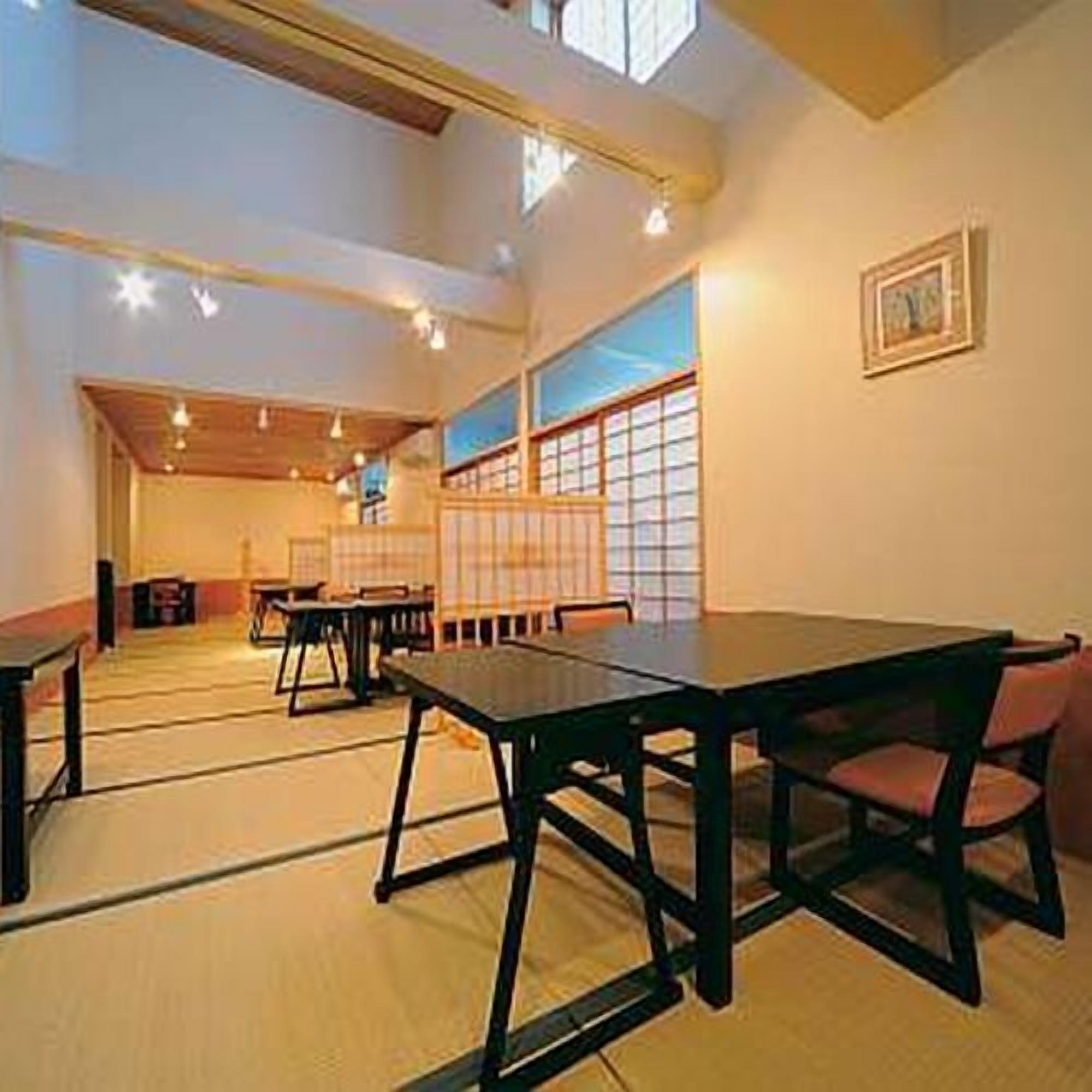A traditional Japanese room with tatami flooring, low tables, and sliding doors.