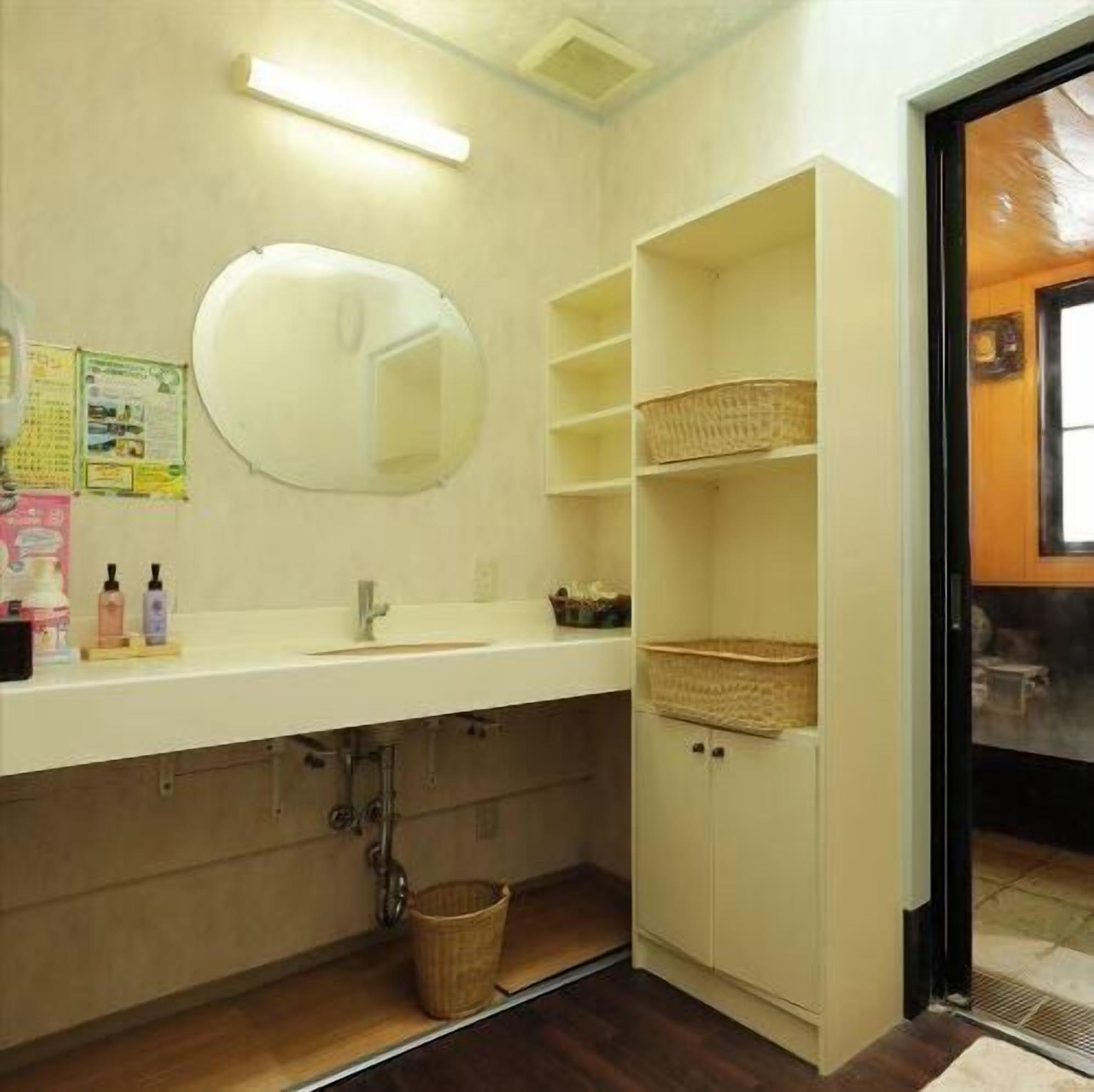 A bathroom with a white sink, mirror, and shelves with baskets.