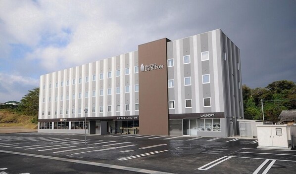 A modern hotel building with a prominent 'Hotel Lexington' sign, a visible laundry facility, and a parking lot. - Hotel Lexton Tanegashima (Nishinoomote)