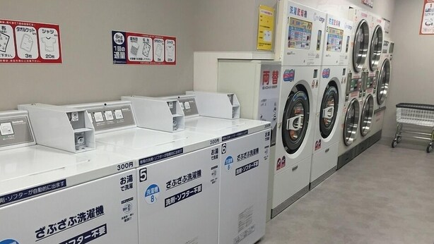 A laundromat with multiple washing machines and dryers, each labeled with Japanese text. - Hotel Lexton Tanegashima (Nishinoomote)