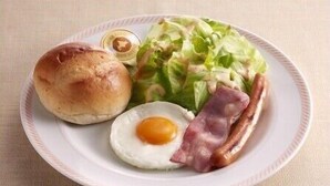 Ein Teller mit einem Brötchen, einem Spiegelei, Speck und einem Salat.