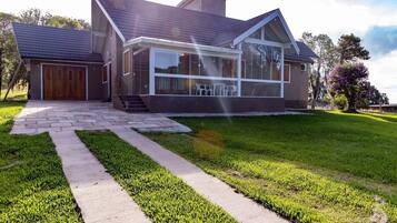Stunning two-story home with a glass facade, central entrance, and beautifully manicured lawn.