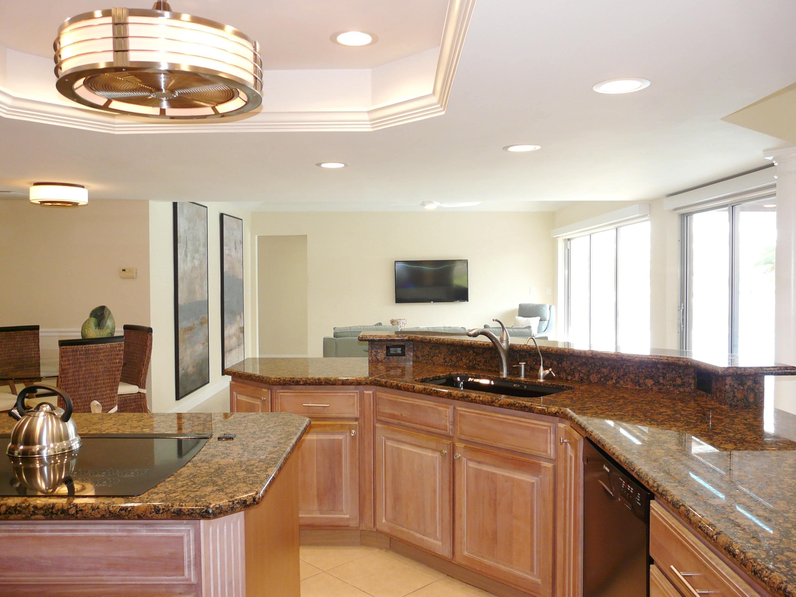 A spacious kitchen with granite countertops, wooden cabinets, and a built-in dishwasher.