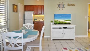 A compact living space with a dining area, kitchenette, and a television on a cabinet. - Aquarius (Marco Island)
