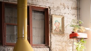 A rustic room with a yellow chimney, a wooden-framed window, a framed portrait, and a potted plant. - Hotel Boutique Lafayette Tijuana (Tijuana)