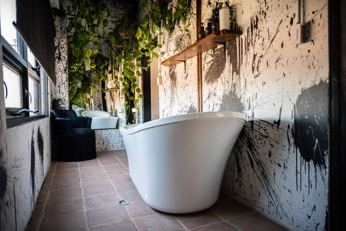 Ein modernes Badezimmer mit einer freistehenden Badewanne, einer schwarzen Sitzbank und einem weißen Waschbecken.