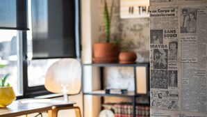A room with a bed, a desk with a lamp, a potted plant, and a wall covered with newspaper clippings. - Hotel Boutique Lafayette Tijuana (Tijuana)