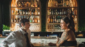 A bar with two patrons seated at a table, surrounded by shelves of bottles. - Hotel Boutique Lafayette Tijuana (Tijuana)