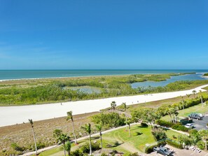 A coastal landscape with a beach, water bodies, and a road leading to a parking area.