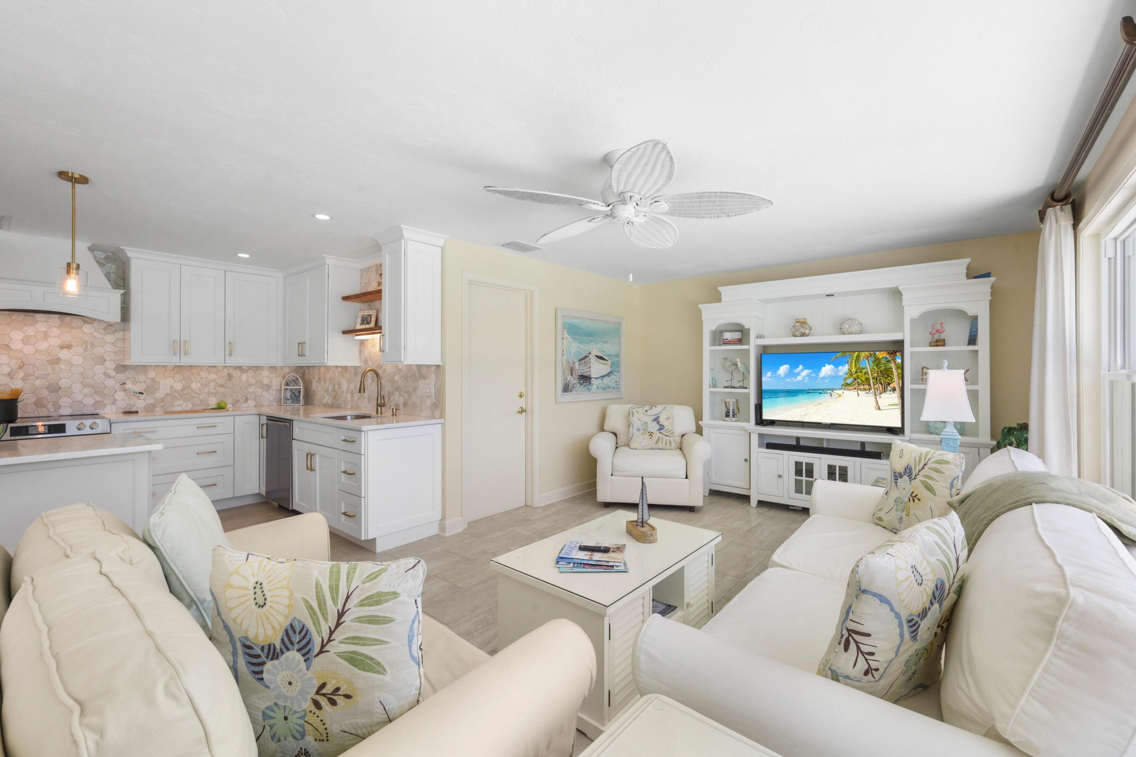 A modern living room with a sofa, coffee table, and a TV displaying a beach scene.