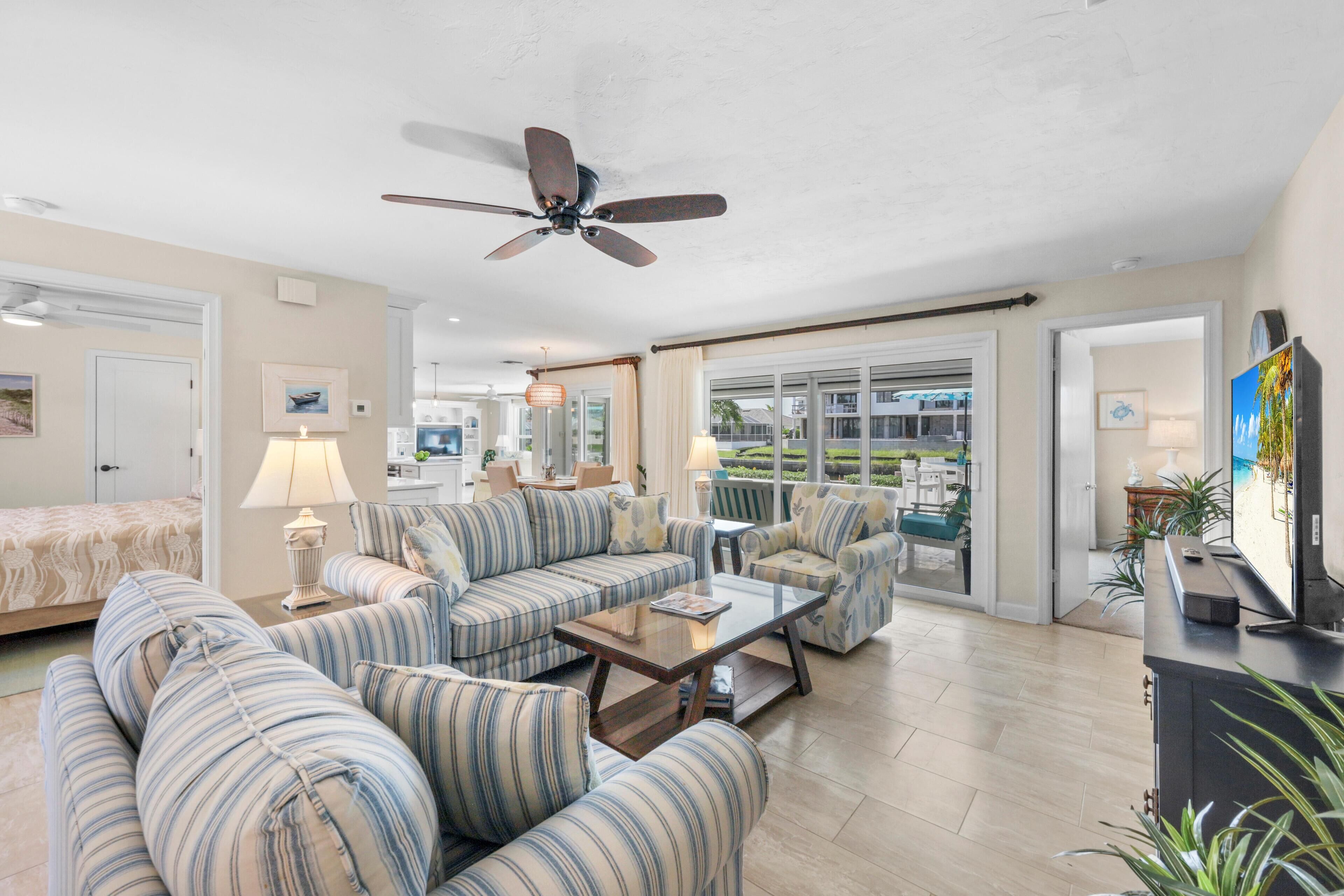 A spacious living room with striped sofas, a coffee table, and a ceiling fan.