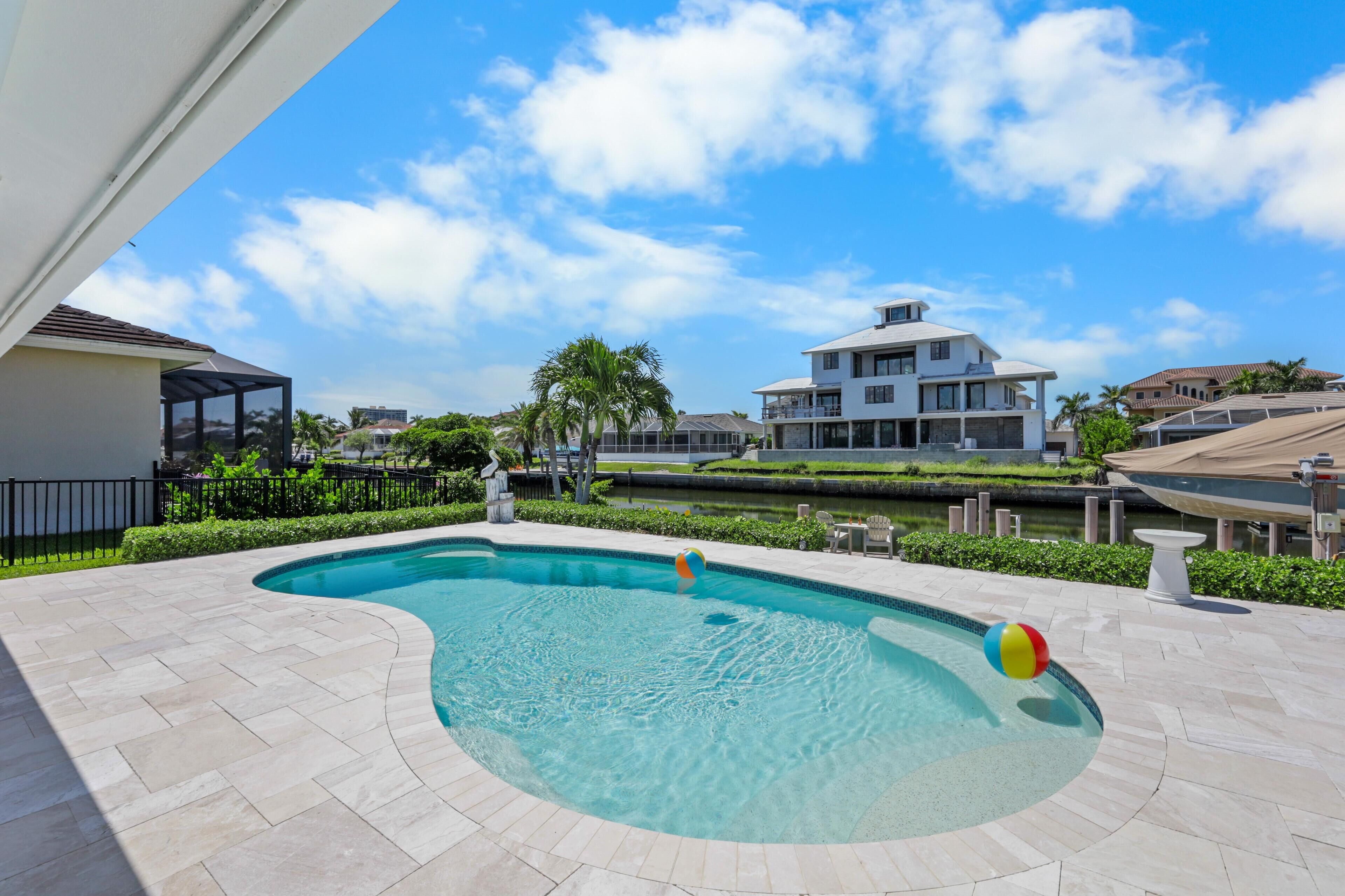 A swimming pool with a curved design, surrounded by a paved deck.