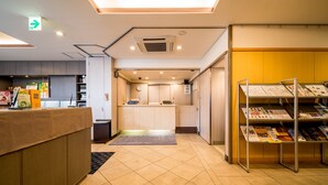 A hotel reception area with a reception desk, a clock, a Wi-Fi sign, and a magazine rack. - Super Hotel Nara Shin Omiya EKI MAE (Nara)