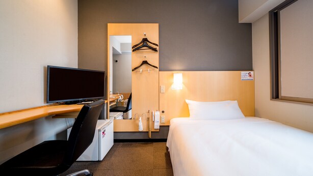 A hotel room with a bed, a desk with a computer, a chair, a TV, a mirror, and a wall-mounted light. - Super Hotel Nara Shin Omiya EKI MAE (Nara)