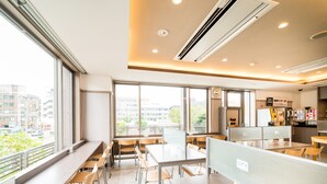 A modern cafe with high tables and chairs, large windows offering city views, and a counter area with a menu display. - Super Hotel Nara Shin Omiya EKI MAE (Nara)