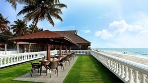 A beachside restaurant with outdoor seating, a covered patio, and a view of the ocean. - Sea Lagoon Health Resort (Cochin)