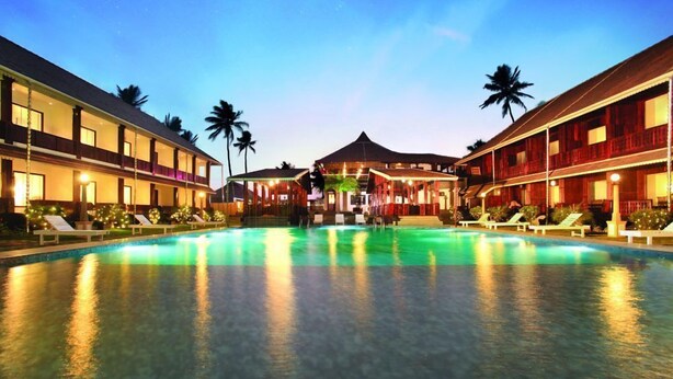 A hotel with a swimming pool, multiple balconies, and palm trees. - Sea Lagoon Health Resort (Cochin)